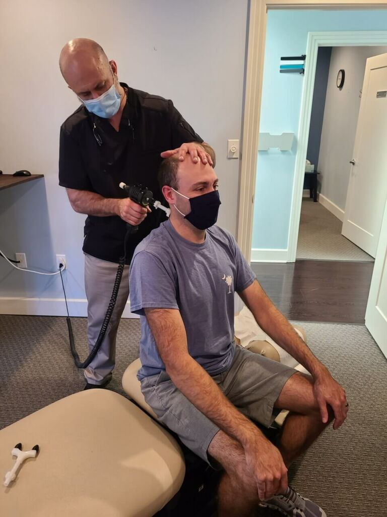 Dr. Michael Elliott using a massage gun on a patient