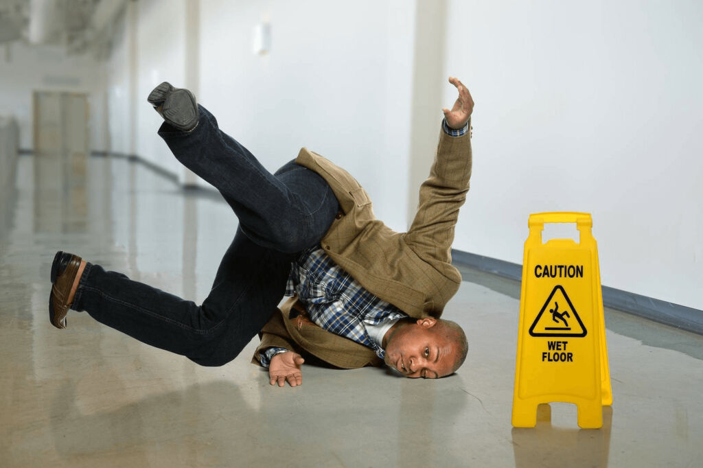 Man falling at a caution wet sign