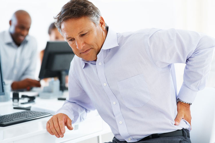 Man slightly hunched over holding his lower back in pain